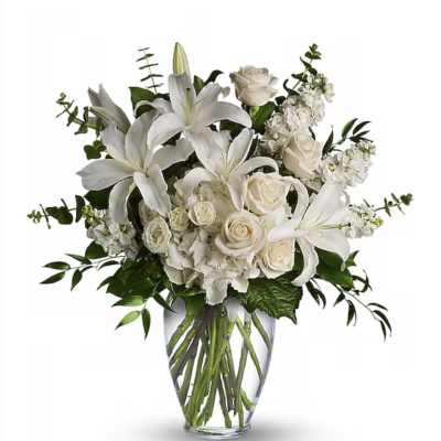 White lilies and roses with other white blooms arranged in a clear glass vase