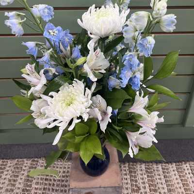 Blue and white flowers arranged in a dark vase