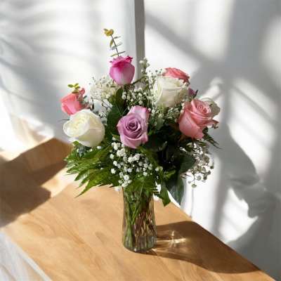 Pink and white roses arranged in a clear glass vase