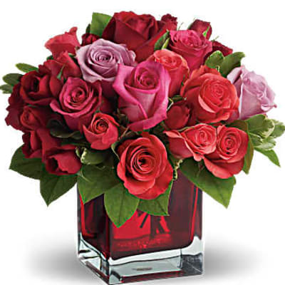 Bouquet of red and pink roses in a red glass vase