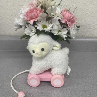 Plush lamb toy with a pink wheeled base and a bouquet of pink and white flowers