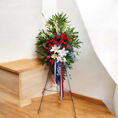 Standing floral spray with red, white, and blue flowers on a metal easel