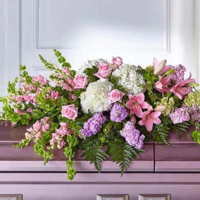 Pink and white floral casket spray with lilies, roses, and hydrangeas