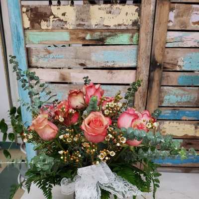Pink roses arranged in a glass vase with lace ribbon
