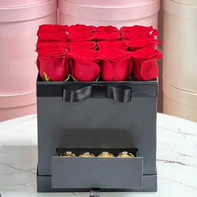 Red roses in a black gift box with a drawer of chocolates
