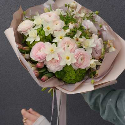 Hand-tied bouquet of pale pink and white flowers wrapped in blush paper