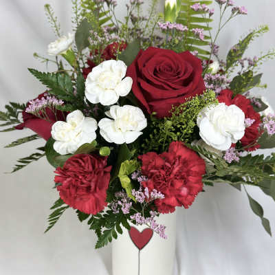 Red roses and white carnations in a white vase.