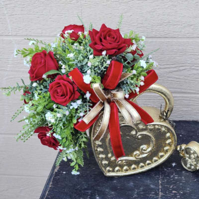 Red roses arranged in a gold heart-shaped container with ribbon.