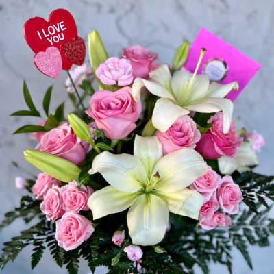 Pink roses and white lilies in a bouquet with an "I LOVE YOU" pick