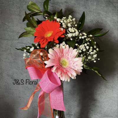 Pink and red gerbera bouquet in a glass vase with ribbon