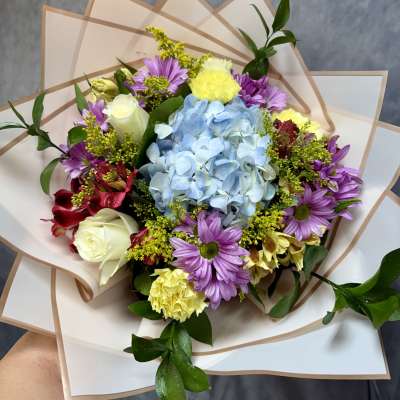 Bouquet with blue hydrangea, purple daisies, and white roses in paper wrap