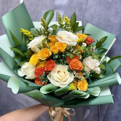 Bouquet of white, yellow, and orange roses wrapped in green paper