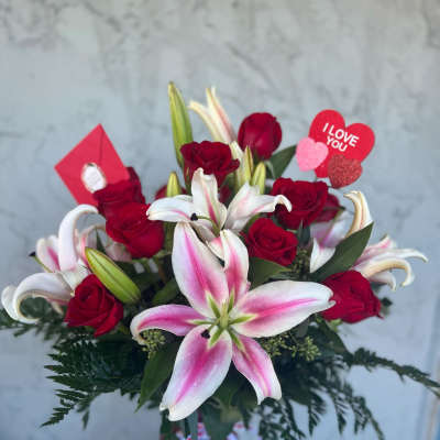 Bouquet of red roses and pink-white lilies in a vase with Valentine hearts
