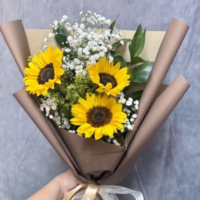 Bouquet of sunflowers and white baby's breath wrapped in brown paper
