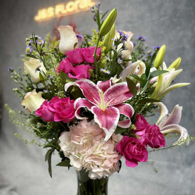 Pink lilies, roses, and carnations in a glass vase