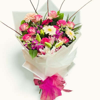 Bouquet of pink roses, white daisies, and lilies wrapped in white paper
