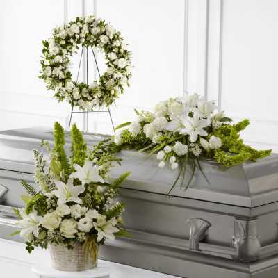 White floral funeral arrangements around a silver casket