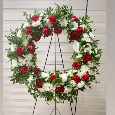 Large red and white floral wreath on a black stand
