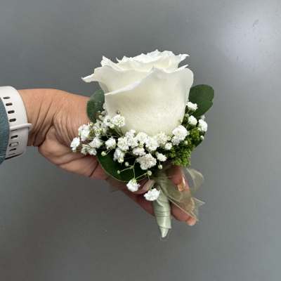 White rose boutonniere with baby's breath and green ribbon