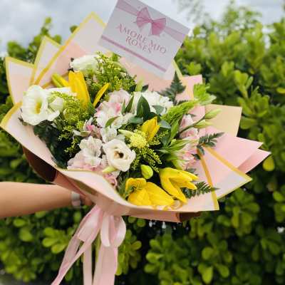 Bouquet of white, pink, and yellow flowers wrapped in pastel paper