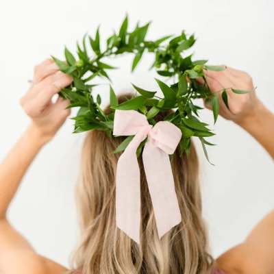 Woman wearing a green leaf crown with a pale pink ribbon