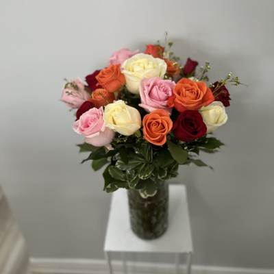 Mixed roses in a glass vase with dark greenery
