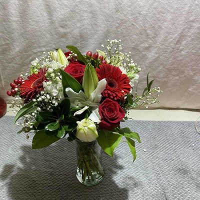 Red roses and gerbera daisies in a clear glass vase