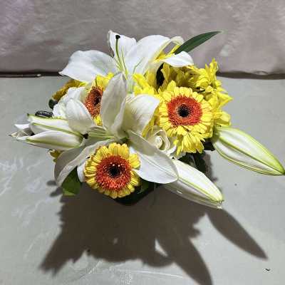 White lilies and yellow gerbera daisies in a low arrangement
