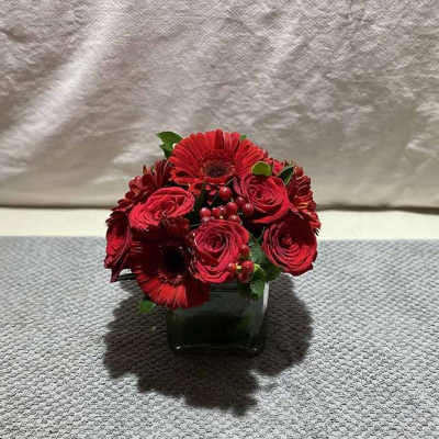 Red rose and gerbera daisy arrangement in a square glass vase