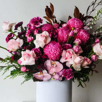 Pink and magenta floral arrangement in a white cylindrical vase