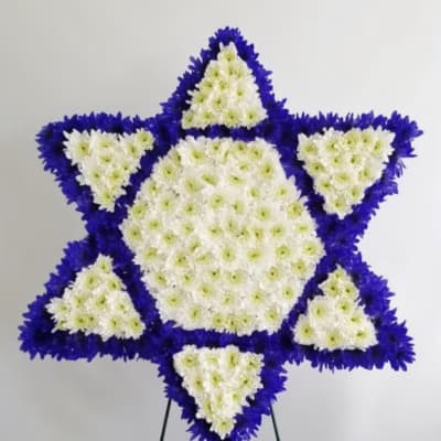 Star-shaped floral wreath of white and purple flowers on a stand