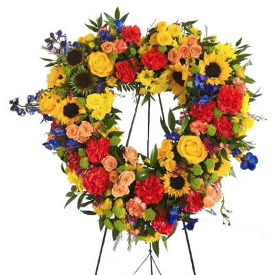 Heart-shaped floral wreath on a stand with mixed bright flowers