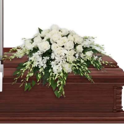 White rose and orchid casket spray arranged on a dark wooden casket.