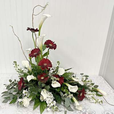 Tall floral arrangement with white calla lilies and deep red daisies