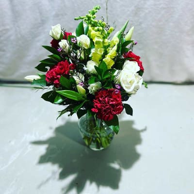 Mixed bouquet of red, white, and green flowers in a glass vase