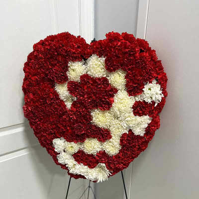 Heart-shaped red and white floral standing arrangement on an easel