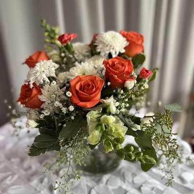 Orange roses and white daisies in a glass vase
