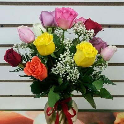 Bouquet of multicolored roses in a glass vase with a red ribbon