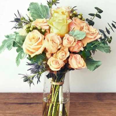 Peach and pale yellow roses in a clear glass vase