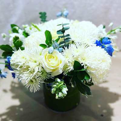 White and blue floral arrangement in a dark vase