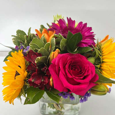 Mixed bouquet with a pink rose, sunflowers, and a glass vase