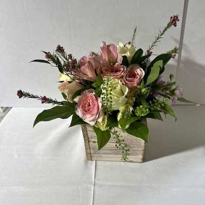 Pink roses and pale blooms in a rustic wooden box