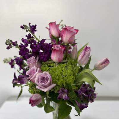 Pink roses and tulips with purple flowers in a glass vase