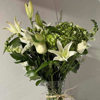 White lilies and green hydrangeas in a clear glass vase