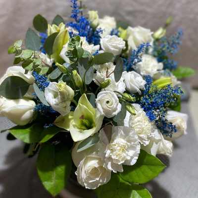 White bouquet with blue accents and green foliage in a vase