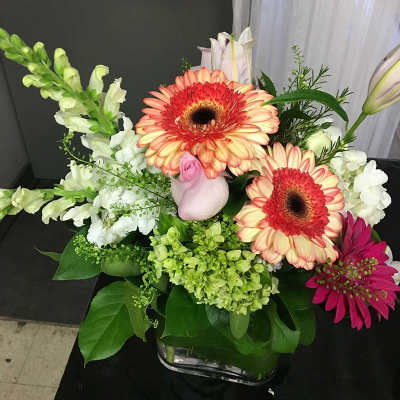 Mixed bouquet with gerbera daisies, snapdragons, and lilies in a glass vase