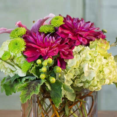 Pink dahlias and green pompons in a clear square vase