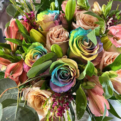 Bouquet of rainbow-dyed roses with pink lilies and greenery