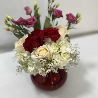 Red and cream roses with white hydrangea in a red vase