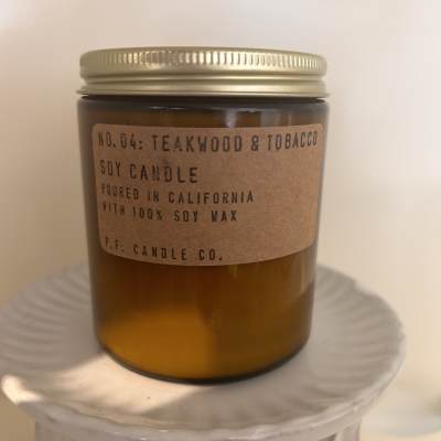 Amber jar candle with a gold lid on a white pedestal